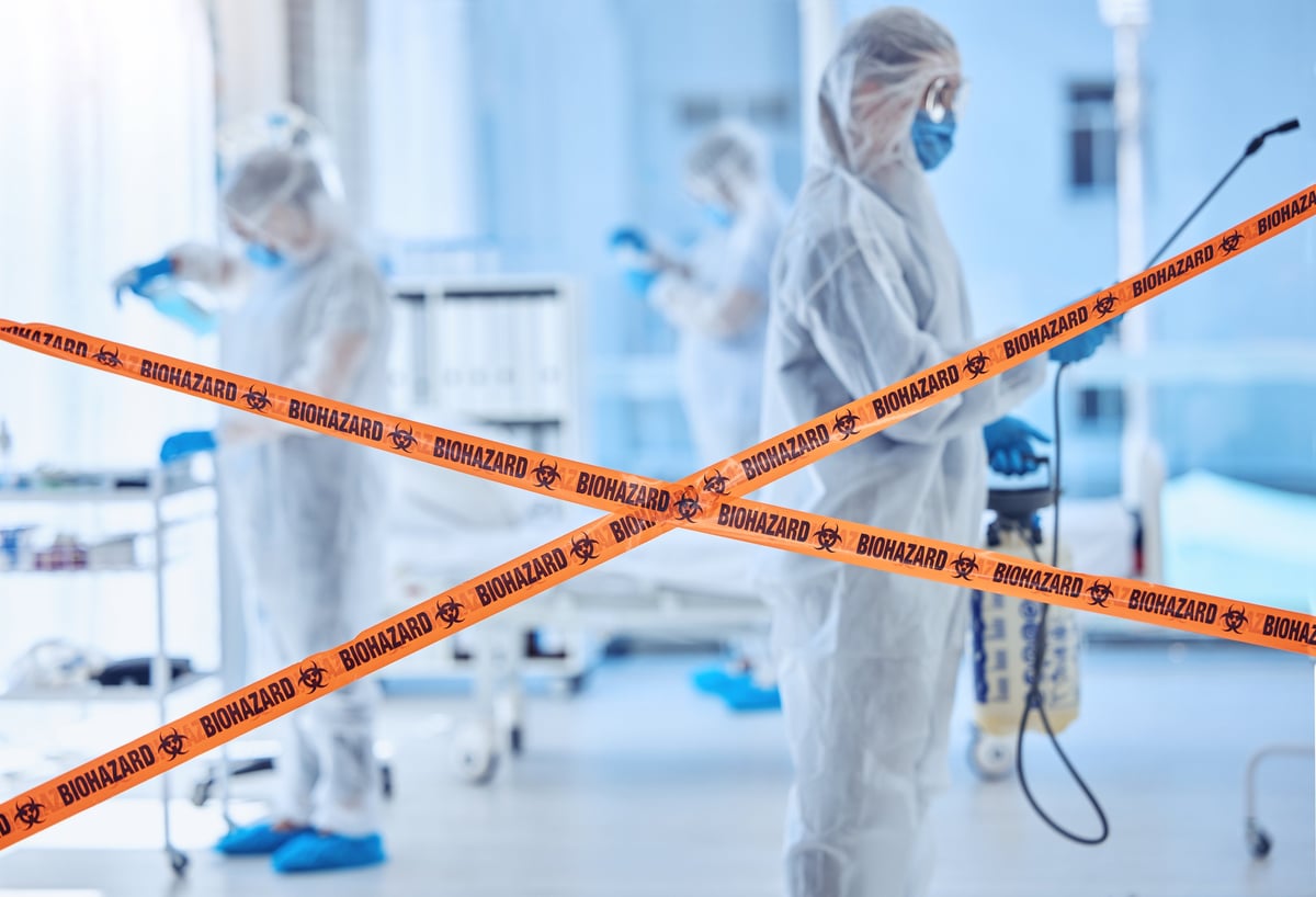 Biohazard remediation specialists in protective suits disinfecting a room